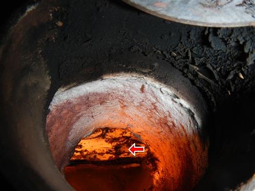 Glowing combustion chamber viewed through a boiler port, with a red arrow marking scale on the heat exchanger.