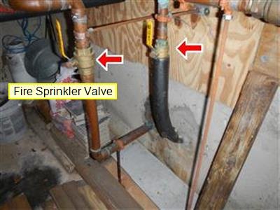 Copper piping with two red arrows at valves and a yellow label reading Fire Sprinkler Valve