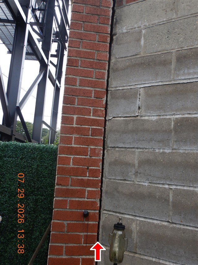 Red arrow at vertical gap where a brick column meets a concrete block wall