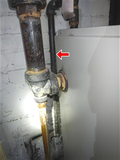 Heavily corroded black steel pipe and fittings beside a white equipment cabinet