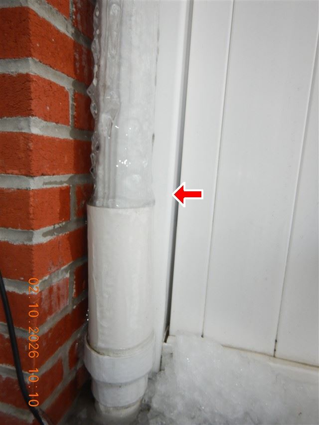 A downspout discharging directly at the base of a brick wall rather than being carried away from the foundation.