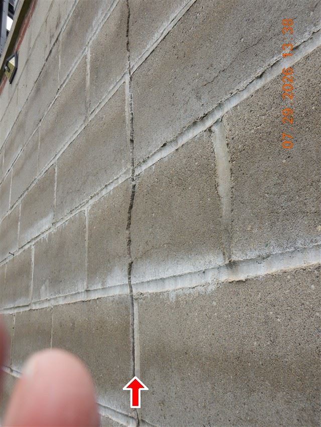 A crack running through a block foundation wall, marked with an arrow in the inspection report.