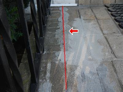 Masonry stoop landing with a red line traced along a patched crack
