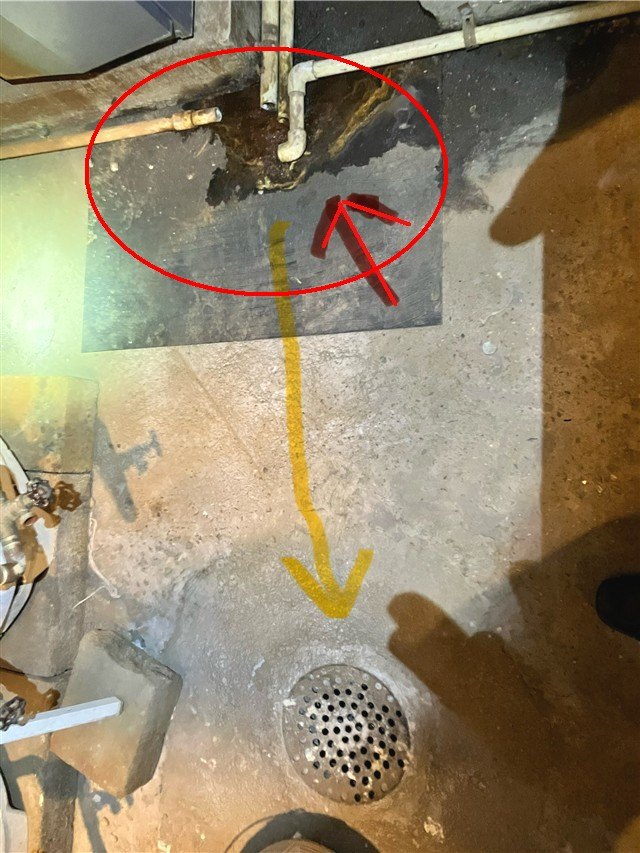 A boiler room floor with a leak area circled in red and an arrow tracing the path to a floor drain.