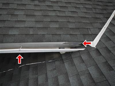 A roof edge with red arrows marking a white metal gutter pulling away from the fascia