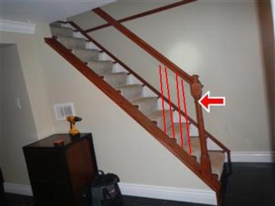 Wood staircase with red lines marking a section of railing missing its balusters, and a red arrow at the handrail