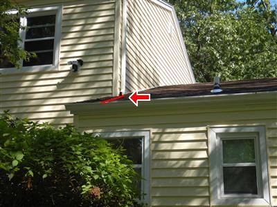 Red arrow and line marking a sag along the edge of a lower roof below a yellow-sided upper story