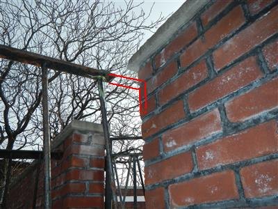 Brick parapet wall and a fire-escape top rail, with a red outline where the unsecured rail end meets the parapet