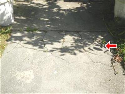 A concrete walkway with cracks running through it, one crack arrowed