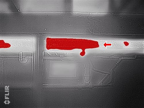 A thermal-camera image with a bright red band showing heat loss along an uninsulated basement duct.