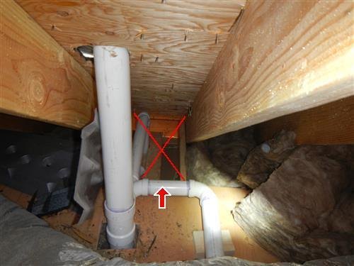 White plumbing vent piping in an attic with a red X marking a rafter bay missing its insulation.