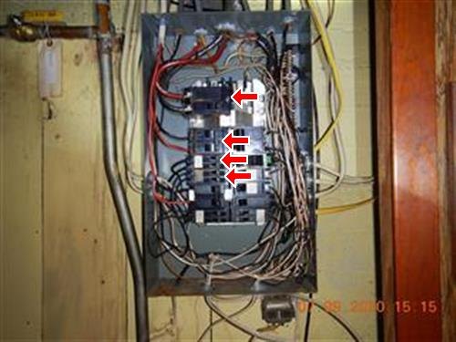 An open electrical panel with red arrows marking the main breaker and water-damaged breakers below it.
