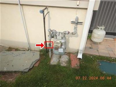Exterior gas meter and piping against a stucco wall, with the whole-house gas shut-off valve boxed in red