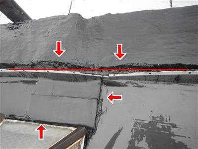 Flat roof parapet wall and skylight edge with open flashing seams marked by red arrows and a red line