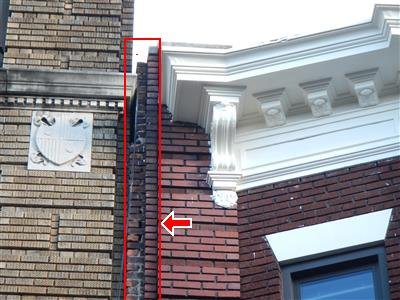 An ornamented brick facade with a red box and arrow marking a corner where the bricks are deteriorated and the mortar joints have eroded