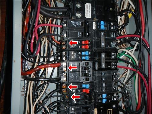 An open electrical panel with red and black wiring and four red arrows marking water-damaged breakers on the left side