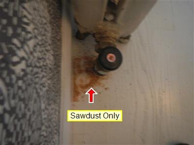 Base of a radiator valve with sawdust on the floor from a borescope test hole, labelled Sawdust Only