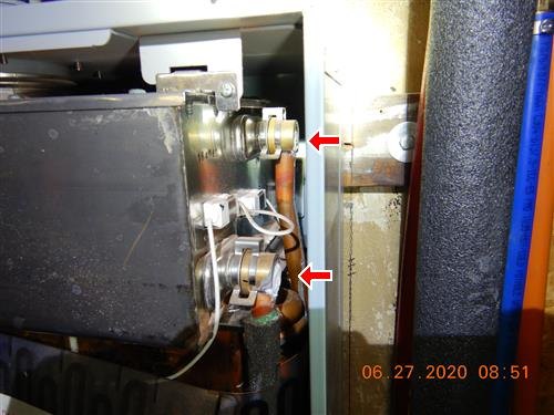 Corroded brass fittings beside a water heater, marked with two red arrows.