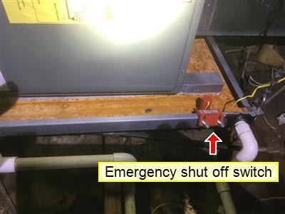 Red emergency shut-off switch mounted beside cooling and air handler equipment, marked with a red arrow and yellow label